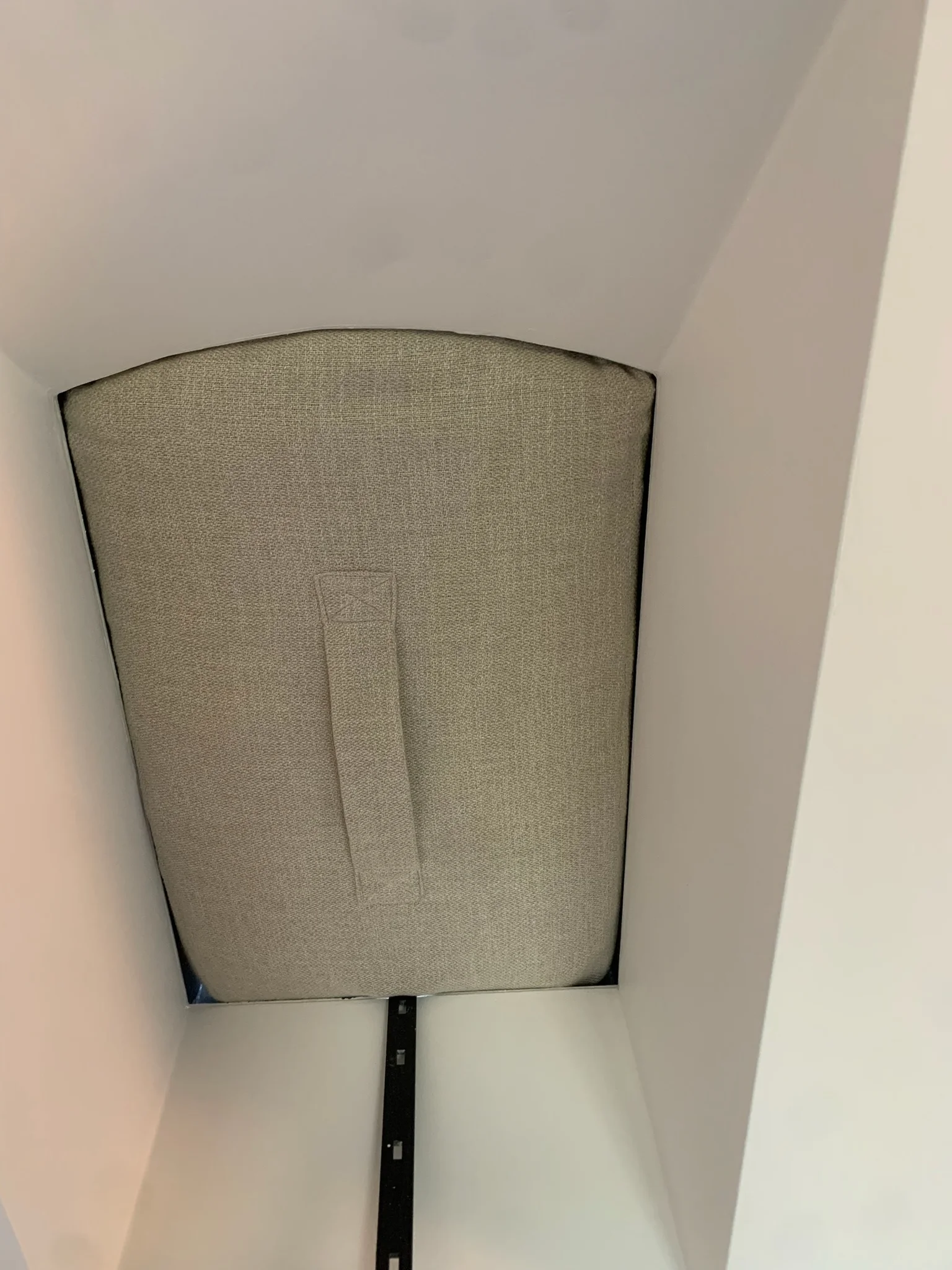 Beige stoffen paneel met handgreep in een muurnis, in een minimalistisch interieur