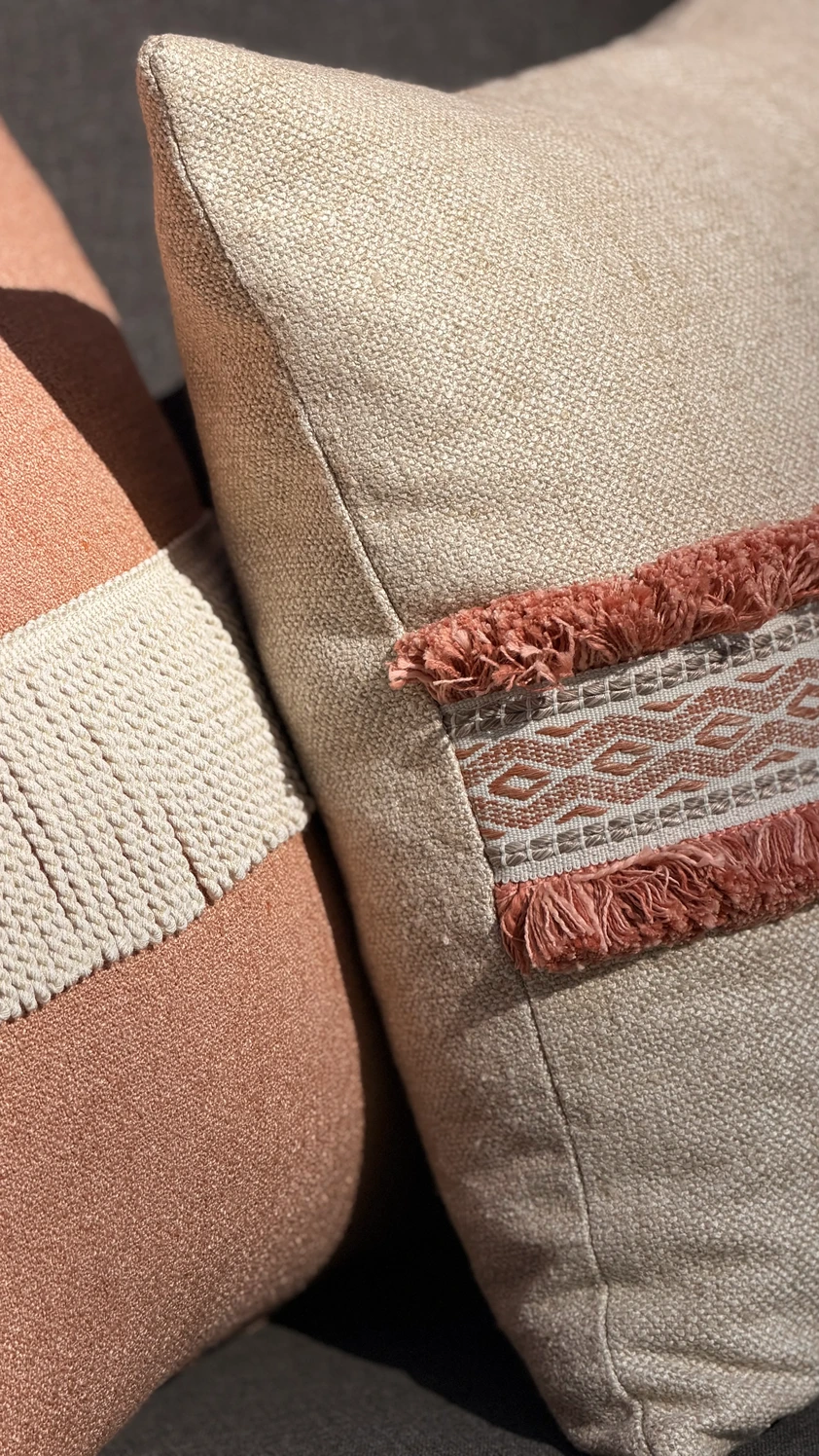 Extreme close-up van sierkussens in terracotta en beige met textielstructuur en boho-franjerand