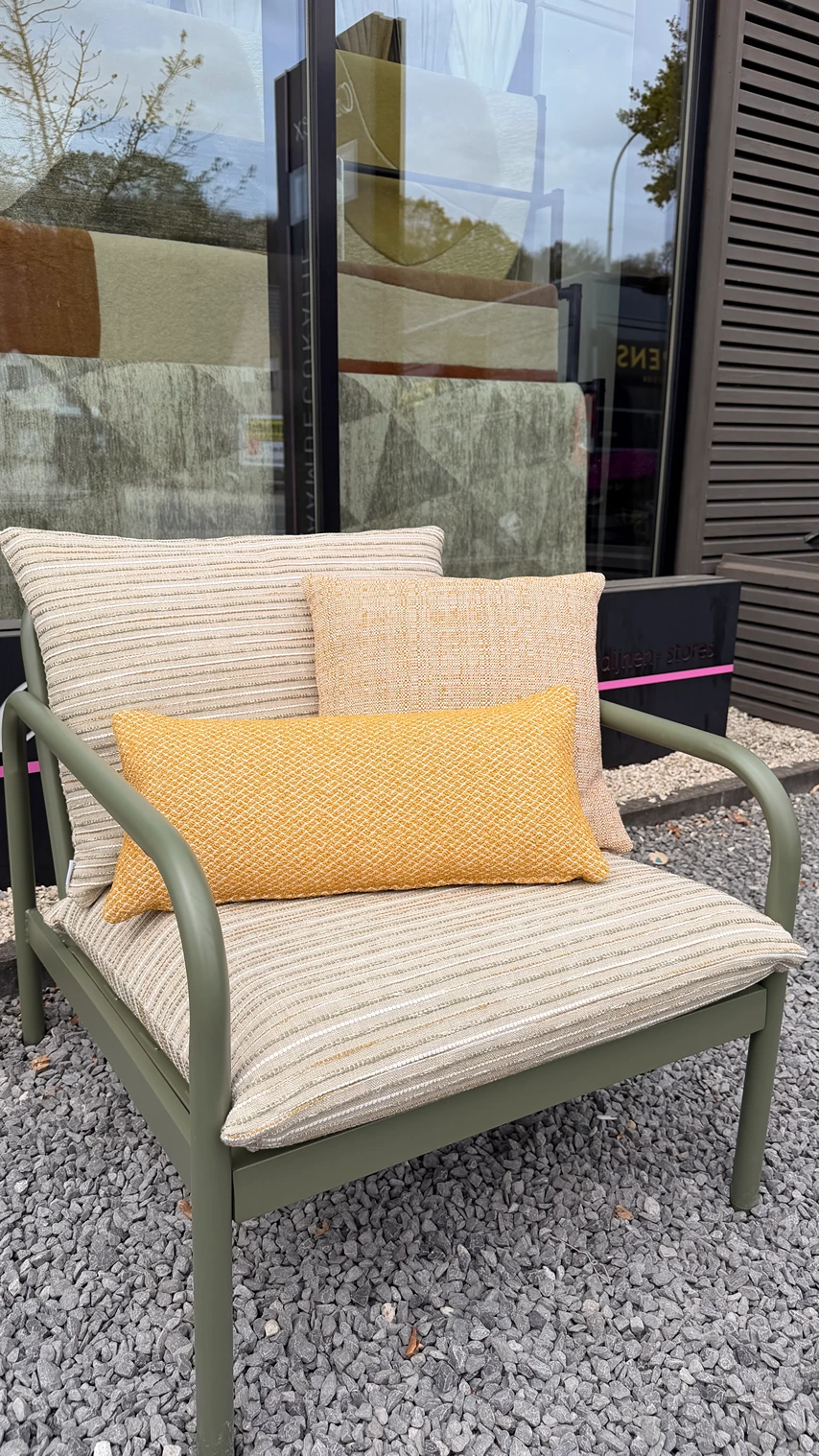 Olijfgroene metalen buitenfauteuil met beige gestreepte kussens en okergele sierkussens