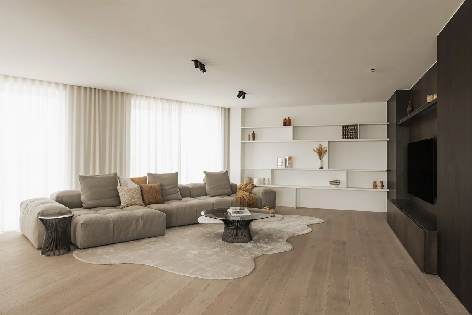 Zachte vitragegordijnen bij het raam van een moderne woonkamer met beige hoekbank en organisch gevormd tapijt